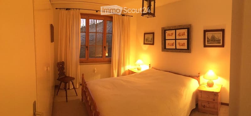 bedroom with a bed, nightstands, lamp, window, curtain, paintings, wooden chair, radiator, wooden cabinet