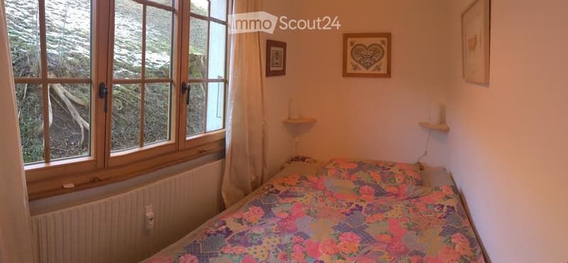 single bed, wooden window frame, curtains, radiator, two picture frames, bedside table