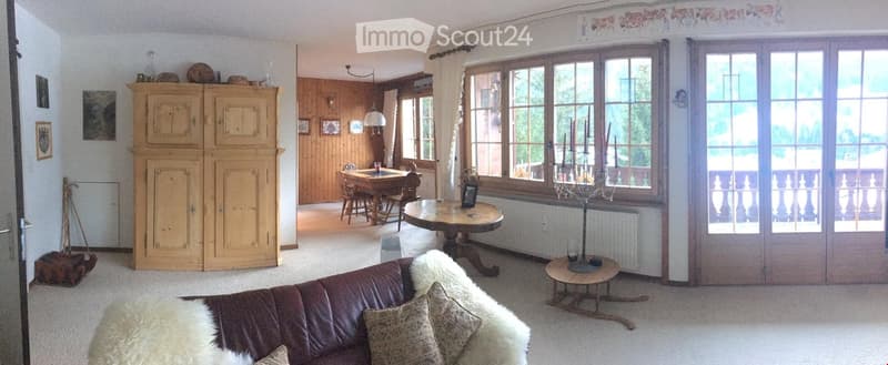 large living room with couch, pillows, wooden table, side table, dining table with chairs, windows, balcony, wooden cabinet