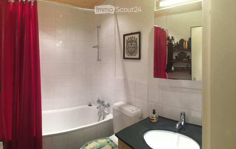 white bathroom with a bathtub, toilet, mirror, countertop, sink, and framed picture