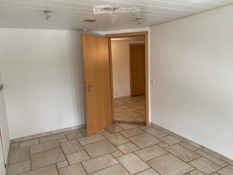 Empty hallway with tiled floor, white walls, and wooden doors leading to other rooms.