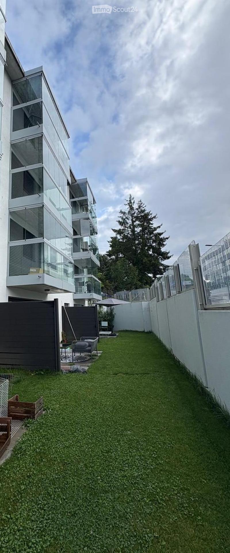 Green lawn, white walls, black fence, glass balconies