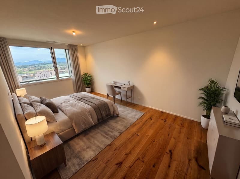 Modern bedroom with a large bed, nightstand, desk, and plants, featuring wooden flooring and large windows with a scenic view.