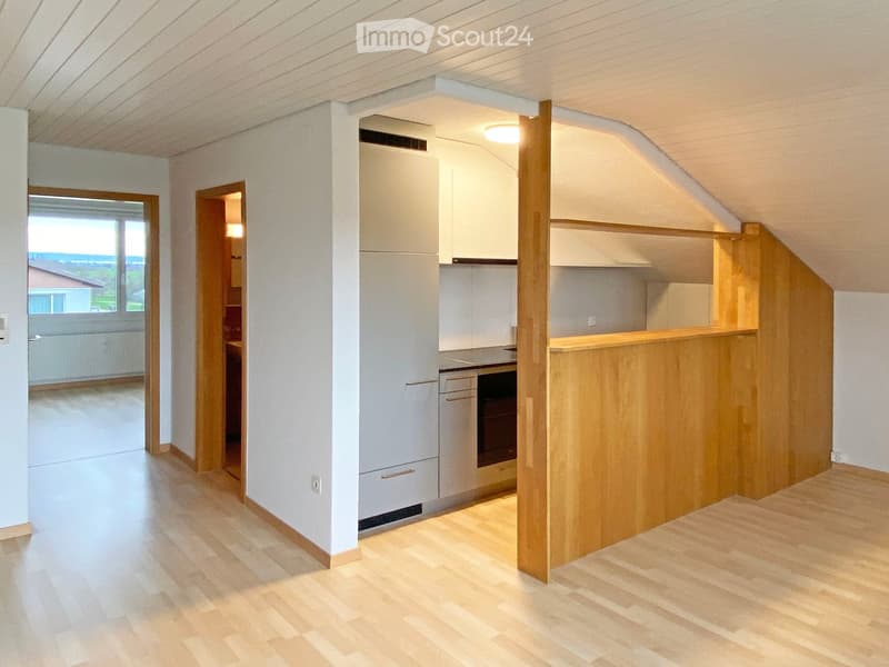 Modern kitchen with light wooden flooring, white cabinets, and a central island. The kitchen features a refrigerator, oven, and a wooden kitchen island with a countertop.