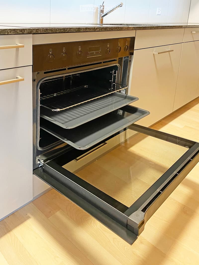 Modern kitchen with an open oven and a faucet on the countertop.