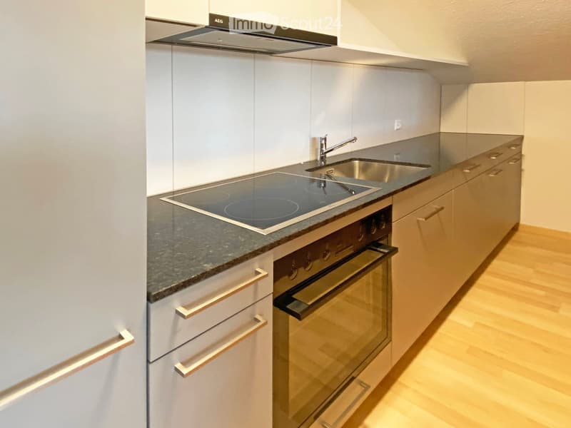 Modern kitchen with white cabinets, granite countertop, induction cooktop, built-in oven, and stainless steel sink.
