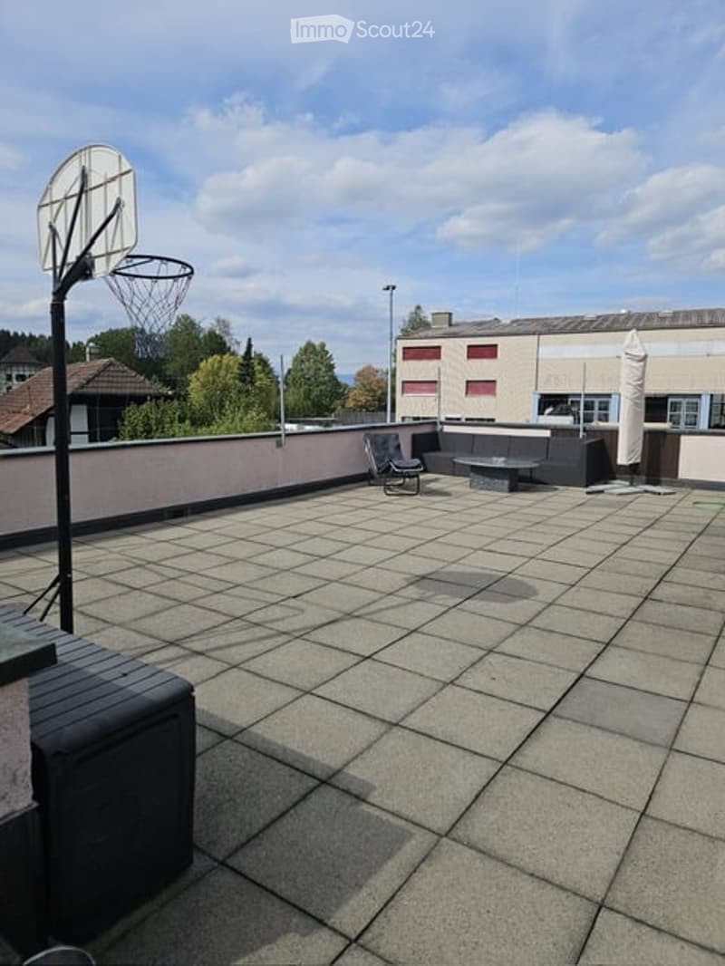 Rooftop terrace with tiled flooring, a bench, a chair, a small table, and a basketball hoop.