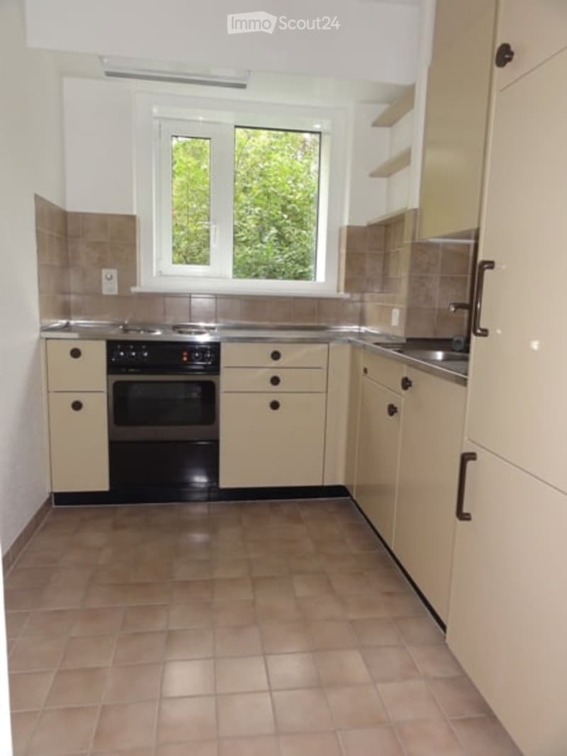Modern kitchen with light-colored cabinets, a black oven, a sink with a faucet, and tiled flooring.
