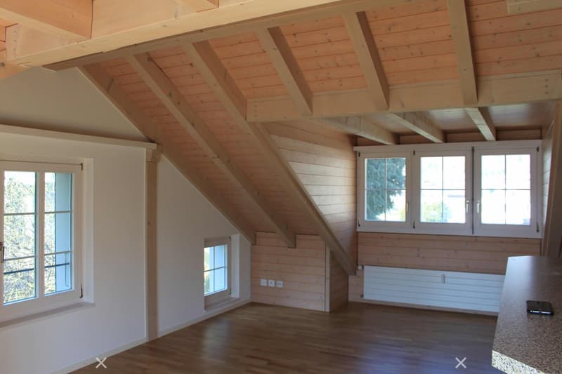 empty attic room with wooden floor, wooden walls and ceiling, white walls, and windows