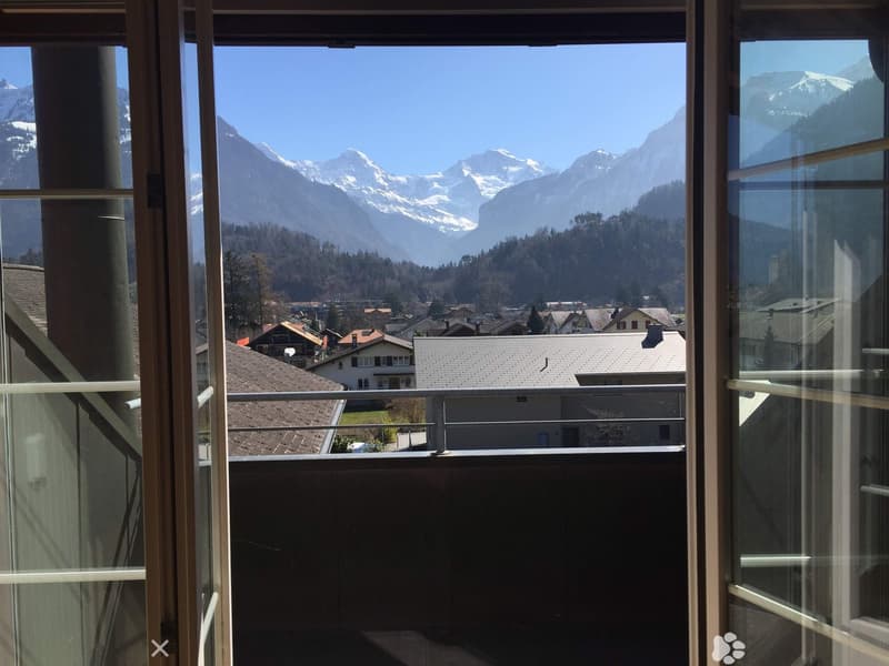 view from balcony, snow-covered mountains, houses, fenced balcony