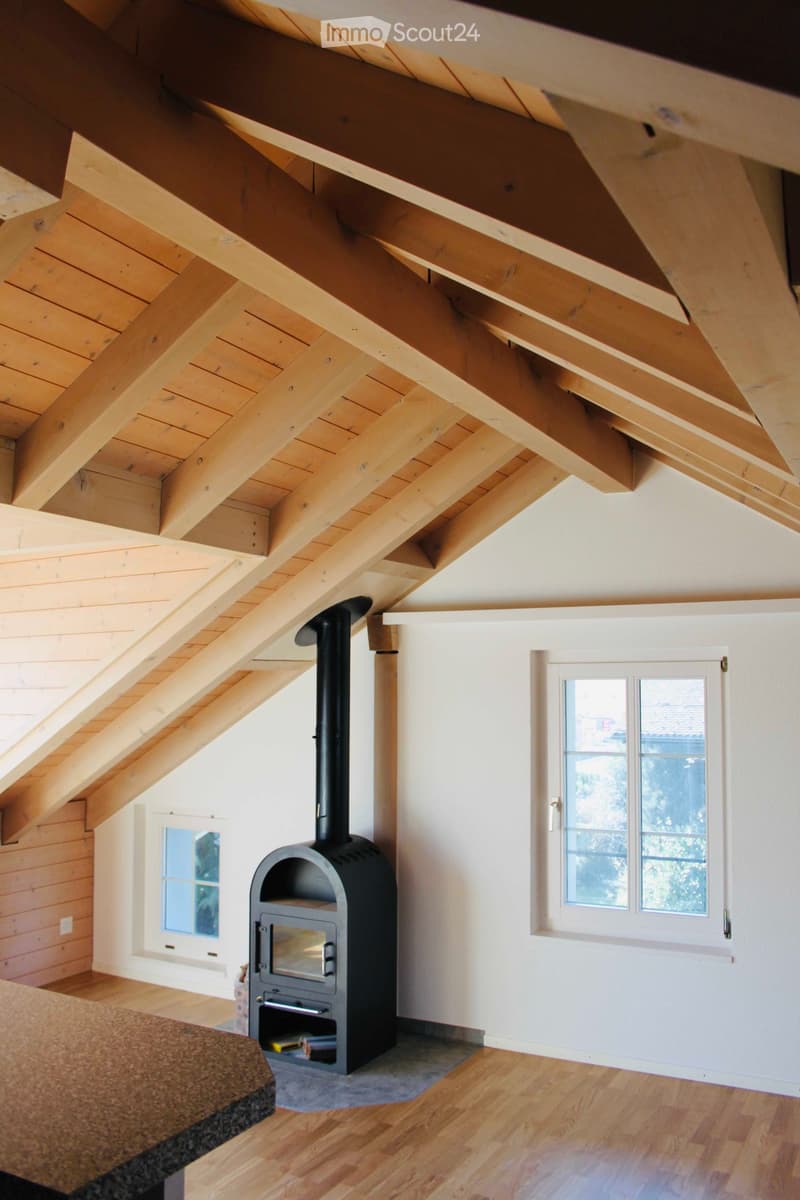 Wooden ceiling beams, fireplace, wooden floor, white walls, windows
