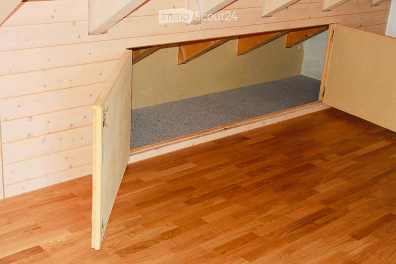 Small attic room with wooden wall, wooden floor, storage compartment with carpet