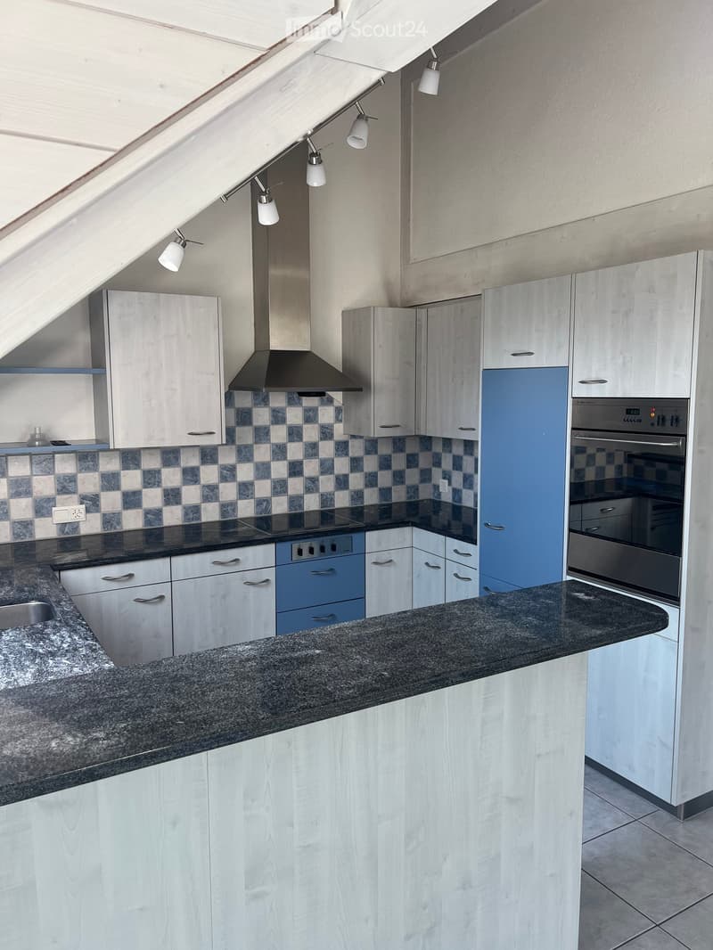 Modern kitchen with white and light blue cabinets, granite countertop, stainless steel appliances, and a checkered backsplash.