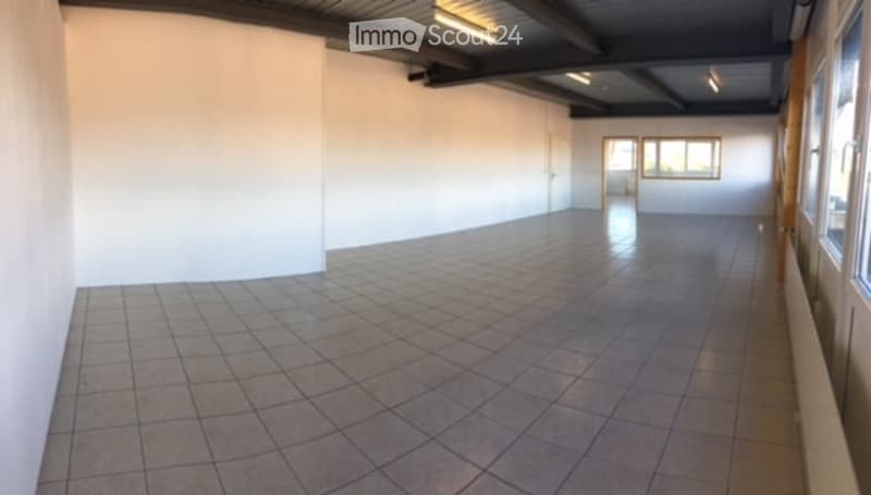 Empty room with white walls, tiled floor, and large windows allowing natural light. No furniture or equipment present.
