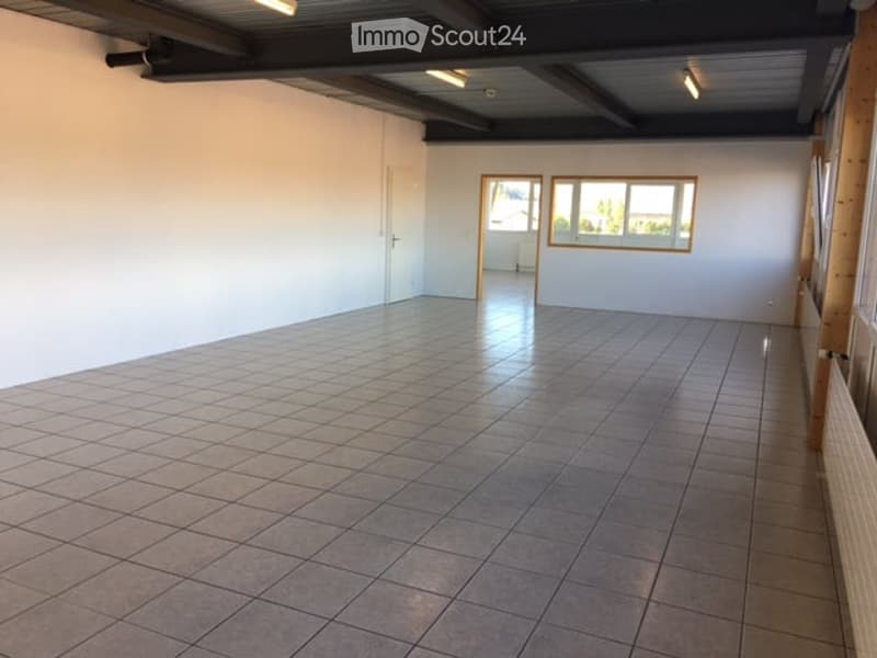 Empty room with tiled floor and white walls, featuring a door and windows with wooden frames.