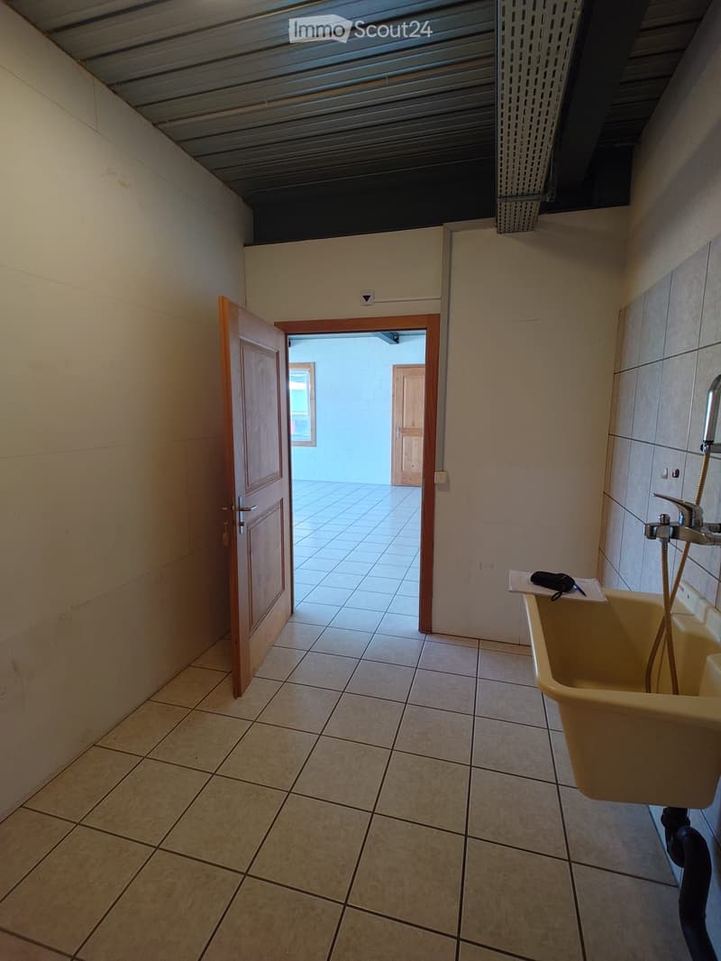 Bathroom with tiled floor and walls, a sink with a faucet, and an open door leading to another room.