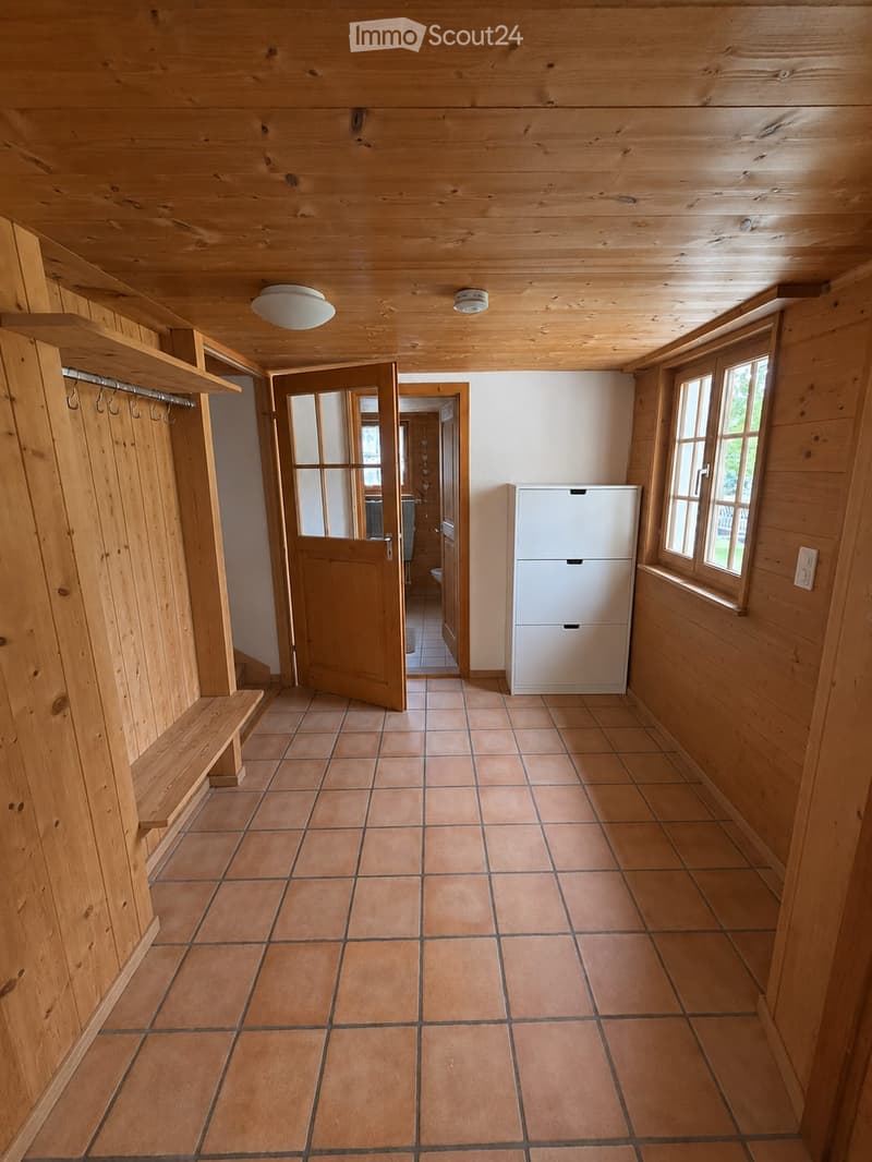 Empty hallway with wooden walls, tiled floor, built-in bench, and open doors leading to other rooms.