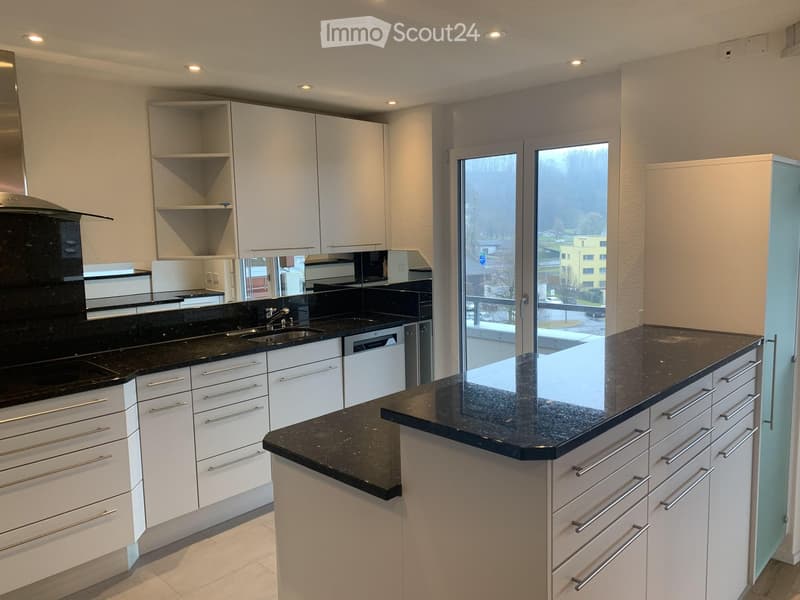 Modern kitchen with white cabinets, black granite countertops, stainless steel appliances, and a large window overlooking the street.