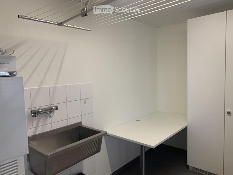 Clean, modern bathroom with a white tiled wall, a stainless steel sink, a faucet, and a white cabinet.