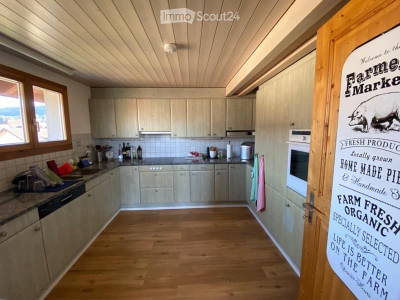 Bright, modern kitchen with light wooden cabinets, granite countertops, and stainless steel appliances. Features include a sink, fridge, oven, toaster, and a towel hanging on the cabinet.