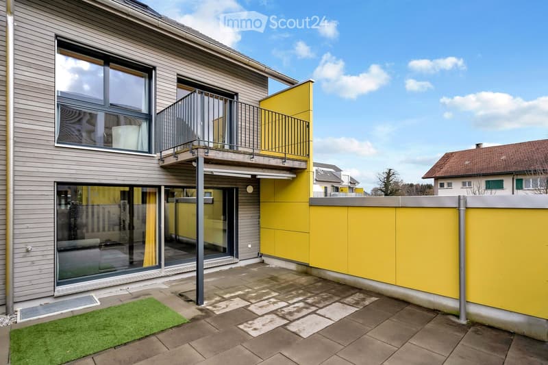 Modern building with yellow exterior wall, balcony, and glass doors.