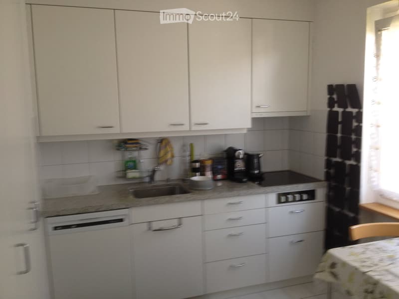 Modern kitchen with white cabinets, stainless steel appliances, and a granite countertop. Includes a sink, coffee maker, oven, and dishwasher.