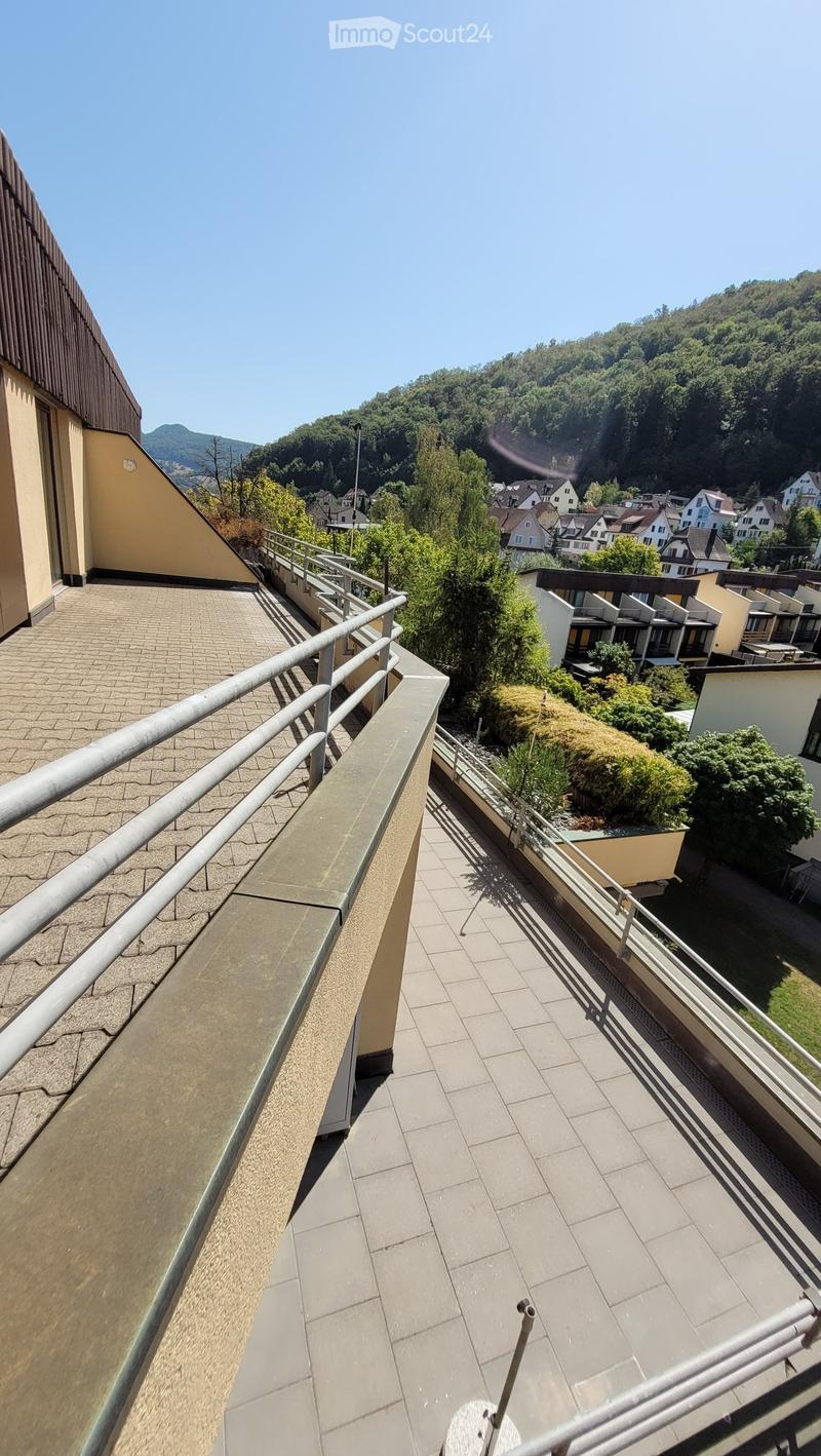 Balcony with tiled flooring, metal railings, and a view of a residential area with houses and greenery.