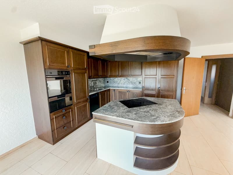 Modern kitchen with wooden cabinets, granite countertop, induction cooktop, and built-in oven.