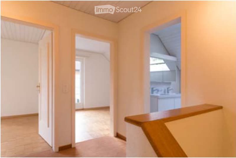 Empty hallway with wooden flooring, white walls, and open doorways leading to other rooms.