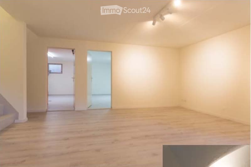 Empty room with wooden flooring, white walls, and two open doors leading to adjacent spaces.