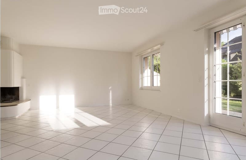 Empty room with white walls, tiled floor, fireplace, and large windows with blinds.