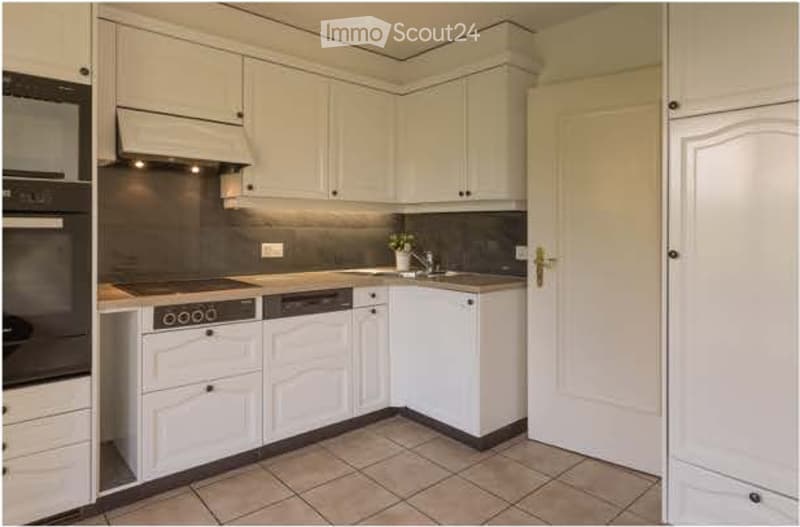 Modern kitchen with white cabinets, stainless steel appliances, and a tiled floor.