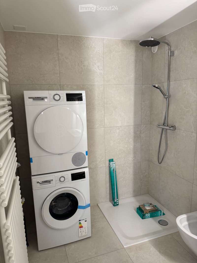 Modern bathroom with a white Bosch washing machine, a shower area, and a radiator.