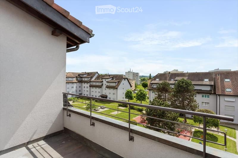 Balcony overlooking a residential area with apartment buildings, green spaces, and trees.
