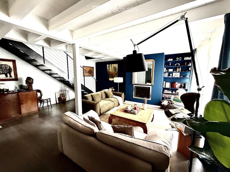 Modern living room with dark blue accent wall, fireplace, two sofas, coffee table, bookshelf, and large floor lamp.