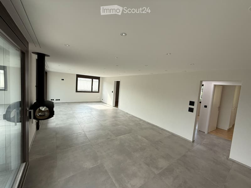Empty room with tiled floor, white walls, recessed ceiling lights, and a fireplace on the left side.