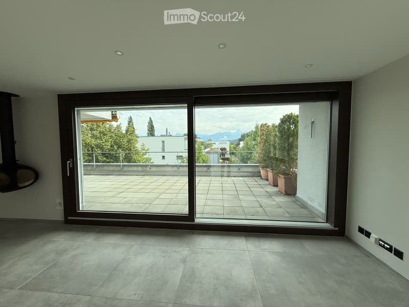 Empty room with large sliding glass doors opening to a tiled balcony, light-colored tiled floor, and recessed ceiling lights.
