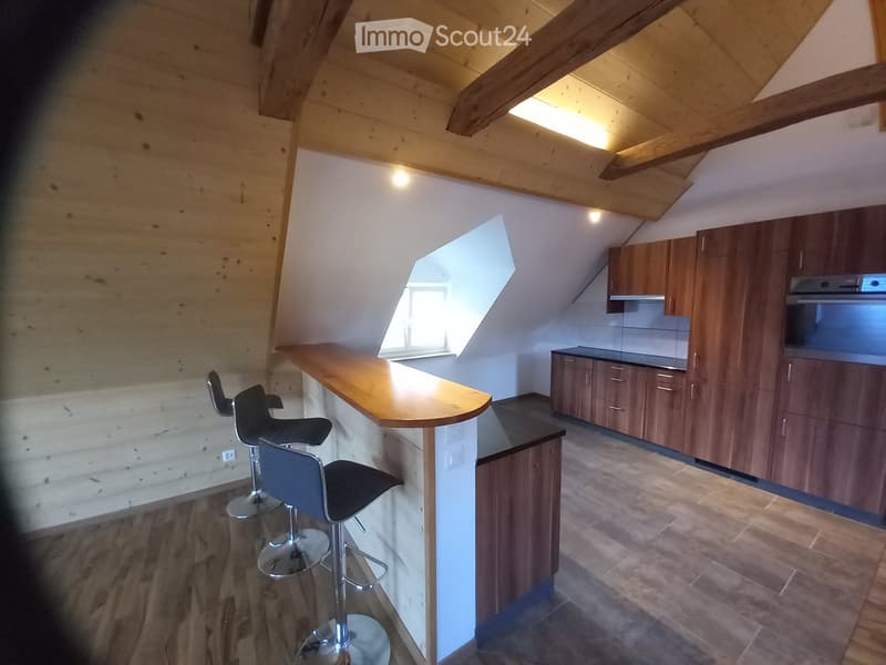 Modern kitchen with wooden cabinets, bar counter, and four black stools. Features a skylight window and sleek design.