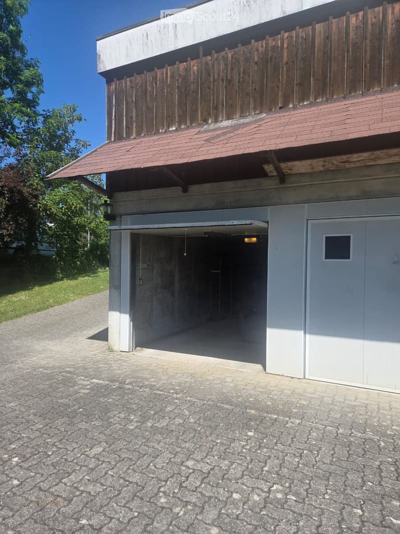 Two-story building with a wooden facade, red-tiled roof, and an open garage entrance.