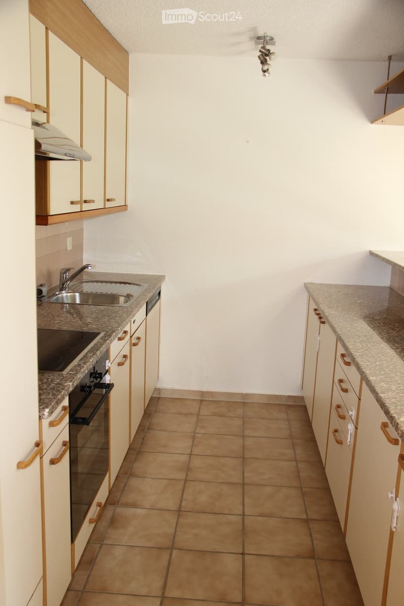 Modern kitchen with light-colored cabinets, granite countertops, and tiled flooring. Features a sink, faucet, and oven.