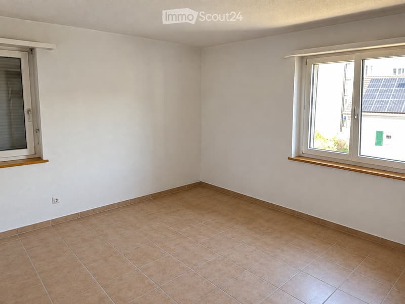 Empty room with tiled floor, white walls, and two windows with blinds. No furniture or equipment present.