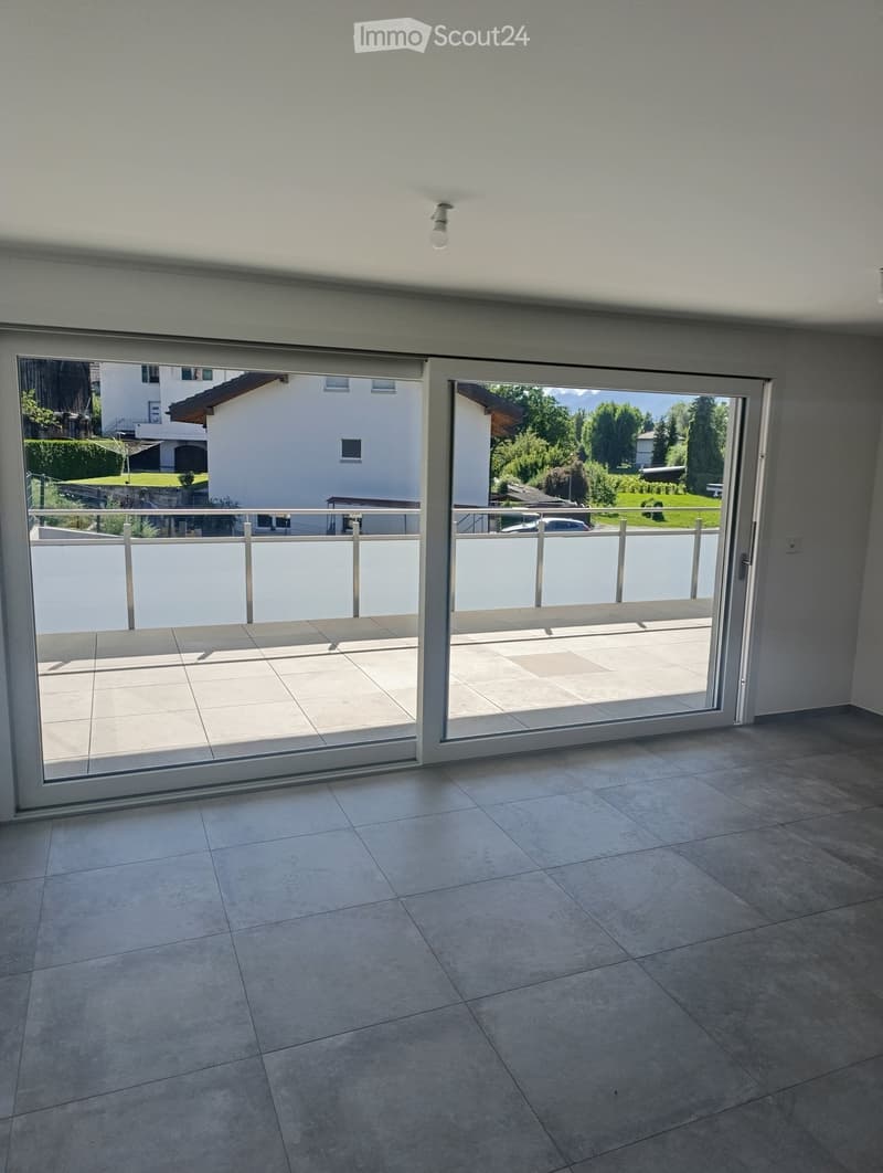 Empty room with large sliding glass doors leading to a balcony, tiled floor, and modern ceiling light fixture.