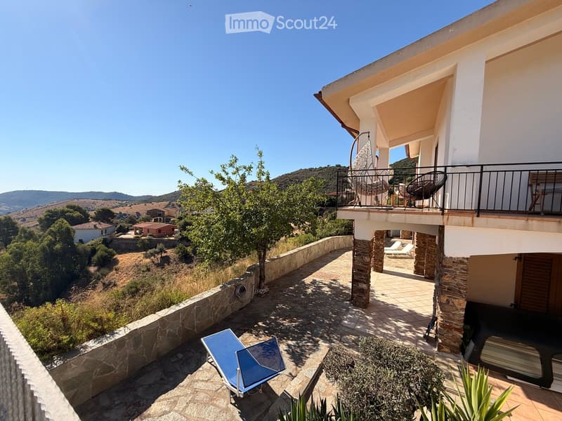 Outdoor patio area with stone flooring, lounge chairs, and a view of the surrounding hills and countryside.