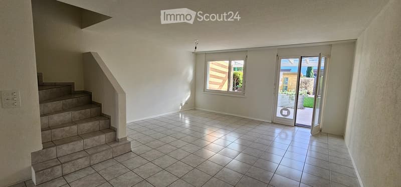 Empty room with tiled floor, staircase leading up, large window, and sliding glass door opening to outdoor area.