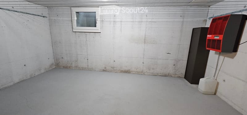 Empty basement room with concrete walls and floor, a small window, and a ventilation unit.