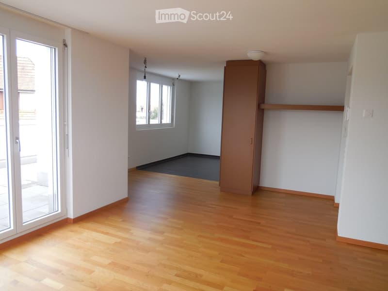Empty room with wooden flooring, white walls, large window, and sliding glass door leading to an outdoor area.