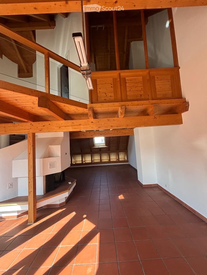 Spacious hallway with terracotta tiled flooring, wooden staircase, and white walls. Natural light filters through a skylight at the far end.
