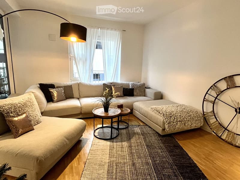 Modern living room with a large sectional sofa, multiple coffee tables, a floor lamp, a large mirror, and a small plant on a table.