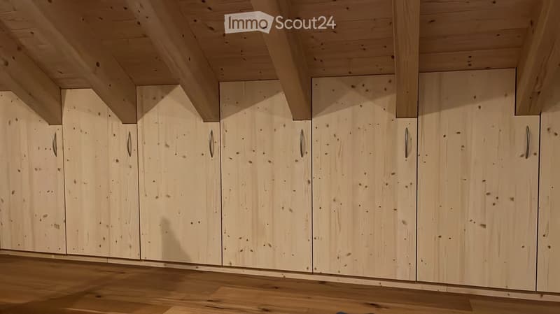 Wooden kitchen cabinets with sleek handles, light wood finish, and a clean, modern design.