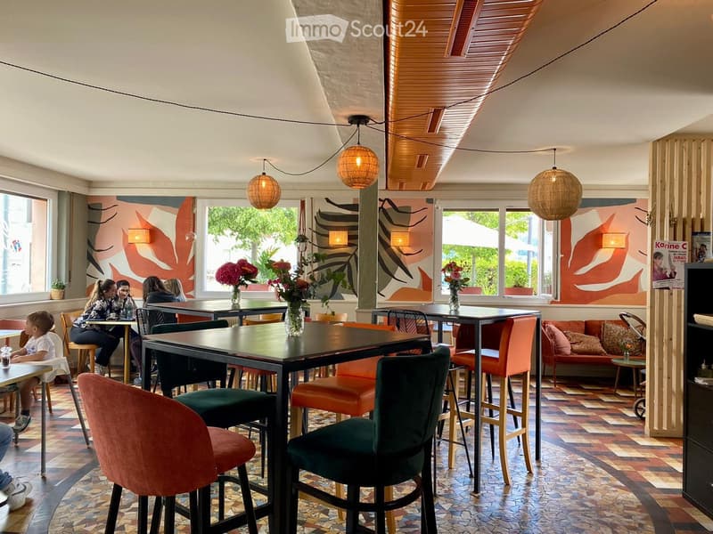 Modern restaurant interior with colorful decor, tables, chairs, and a sofa area.